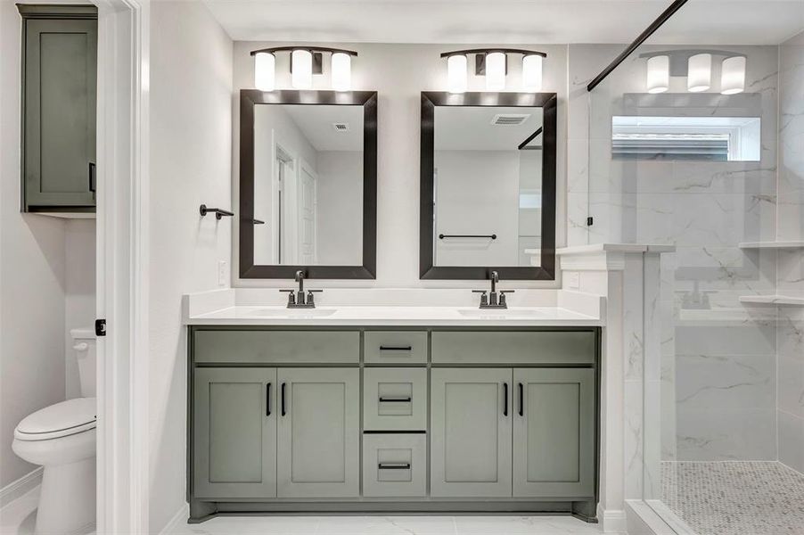 Full bathroom featuring double vanity, a marble finish shower, and light marble finish flooring