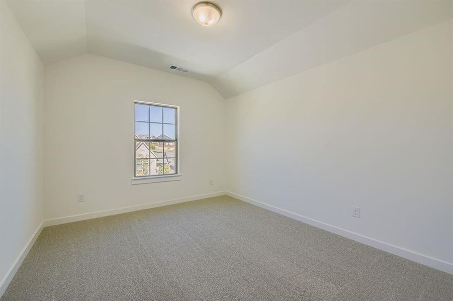 Unfurnished room featuring light colored carpet and lofted ceiling Unfurnished room featuring light colored carpet and lofted ceiling