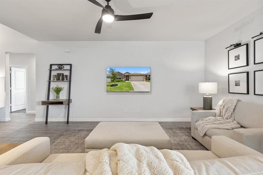 Living area with vinyl wood floors, ceiling fan, and baseboards Living area with vinyl wood floors, ceiling fan, and baseboards