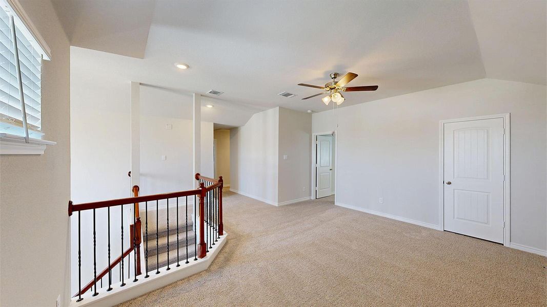 This versatile area features light-colored carpeting, a ceiling fan, and recessed lighting, offering a bright and inviting atmosphere