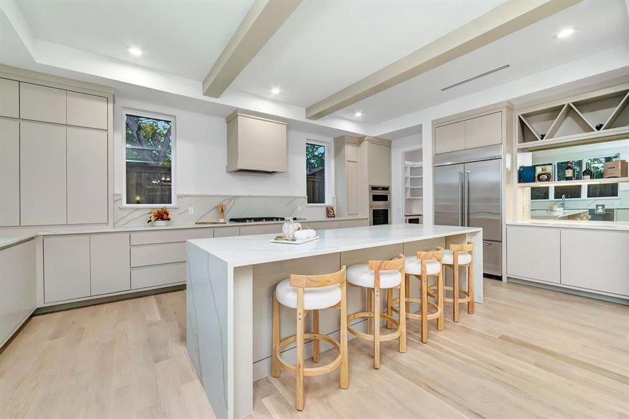 Kitchen with a breakfast bar, stainless steel appliances, light wood finished floors, a center island, and beamed ceiling Kitchen with a breakfast bar, stainless steel appliances, light wood finished floors, a center island, and beamed ceiling