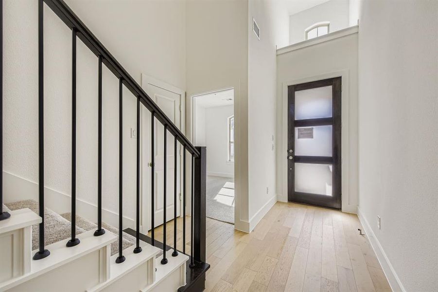 Foyer featuring light wood finished floors, stairs, and a high ceiling Foyer featuring light wood finished floors, stairs, and a high ceiling