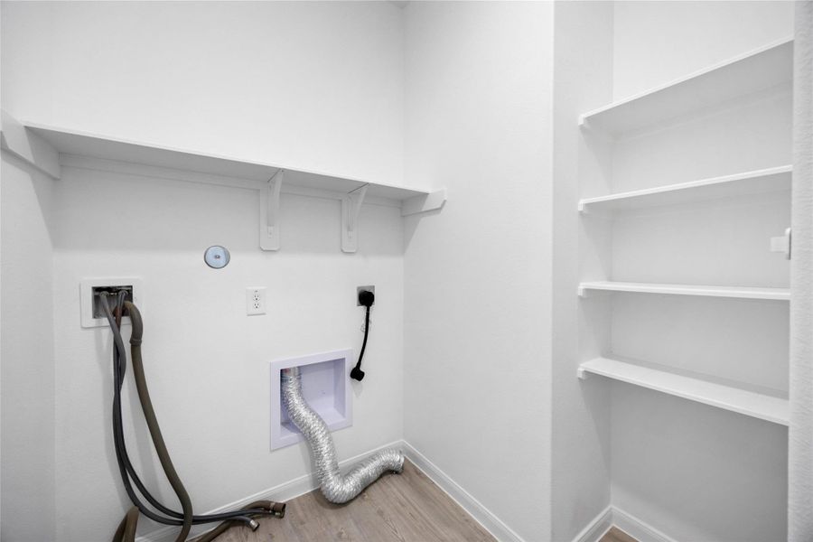 laundry room with hookups for a washer and dryer. It features built-in shelving for storage and a clean, modern design.