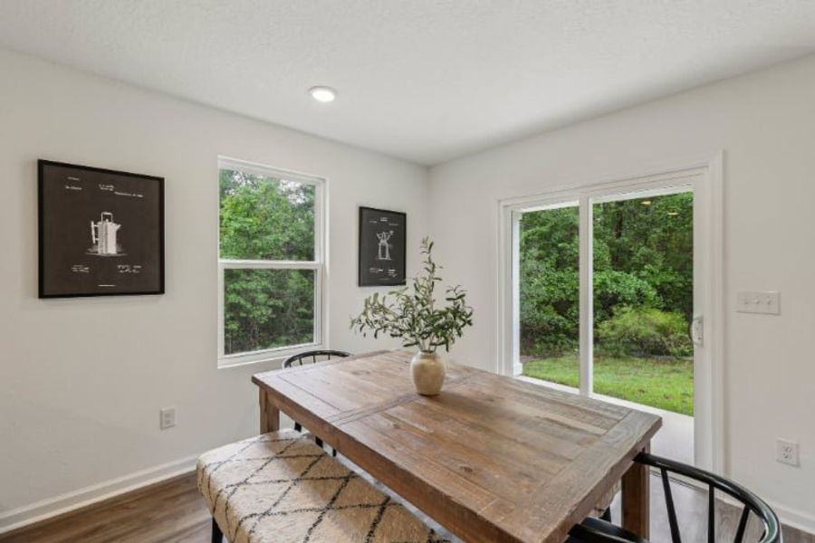 A table with a vase of flowers on it in a room with windows.