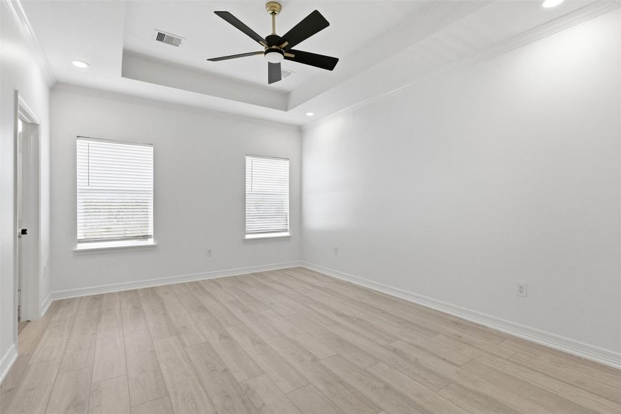 Bright second floor bedroom with tray ceiling, ceiling fan, and large windows — light, airy, and move in ready.