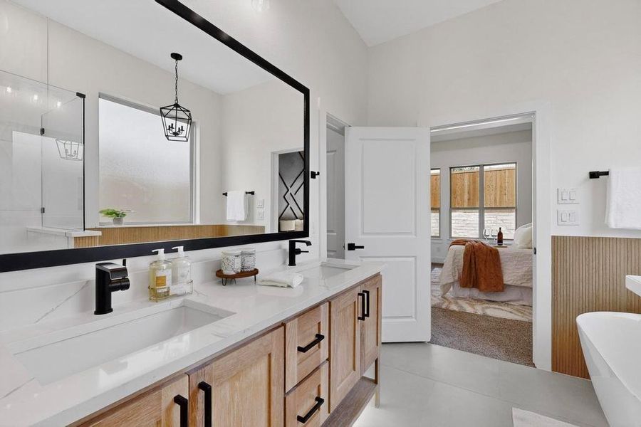 Ensuite bathroom featuring double vanity, a soaking tub, and a wainscoted wall