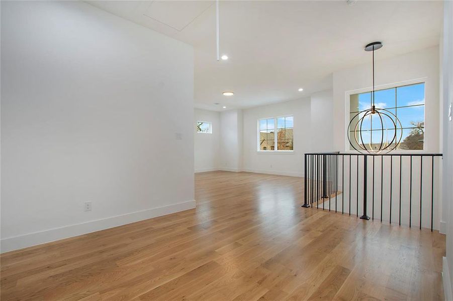 Unfurnished room with light wood-style floors, a chandelier, baseboards, and recessed lighting Unfurnished room with light wood-style floors, a chandelier, baseboards, and recessed lighting