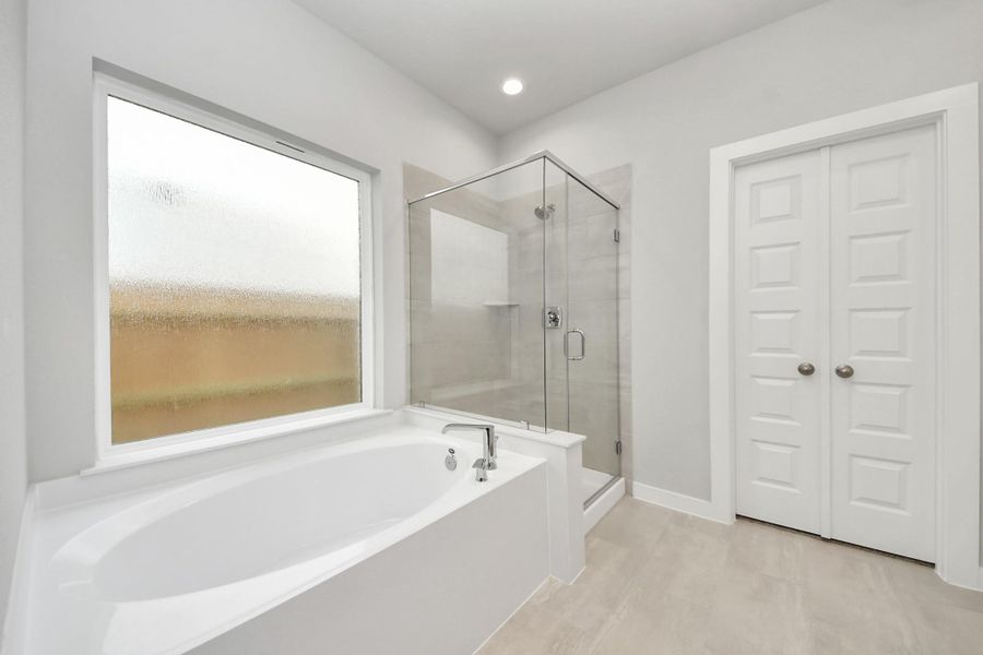Indulge in a spa-like retreat within the confines of this primary bathroom. Delight in a spacious walk-in shower enveloped in stylish tile surround and unwind in a separate garden tub adorned with custom detailing.