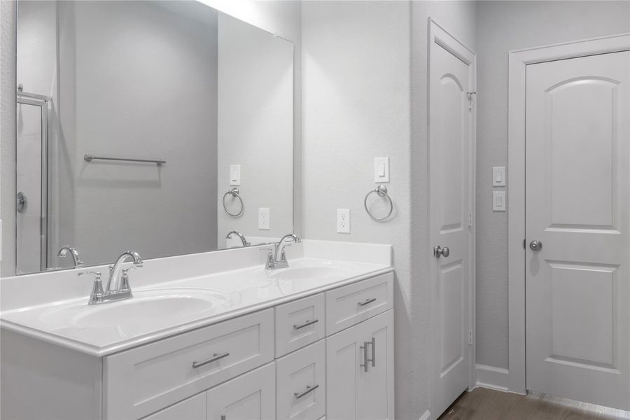 This bathroom features a modern double-sink vanity with sleek chrome fixtures, ample storage, and a large mirror. The neutral color palette enhances the clean, spacious feel.