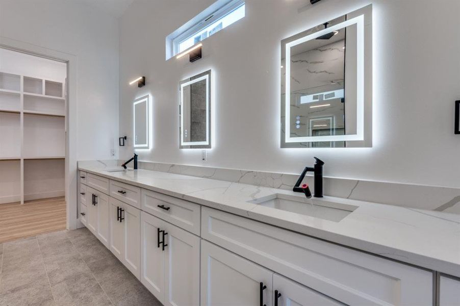 Spa-like primary bathroom with an expansive 14-foot vanity illuminated by anti-fog lighting mirrors, a spacious walk-in closet, and a soaking tub alongside a multi-head shower for the ultimate relaxation experience. Spa-like primary bathroom with an expansive 14-foot vanity illuminated by anti-fog lighting mirrors, a spacious walk-in closet, and a soaking tub alongside a multi-head shower for the ultimate relaxation experience.