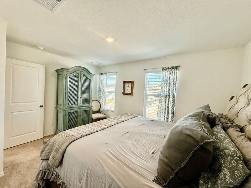 Carpeted bedroom featuring a textured ceiling and baseboards