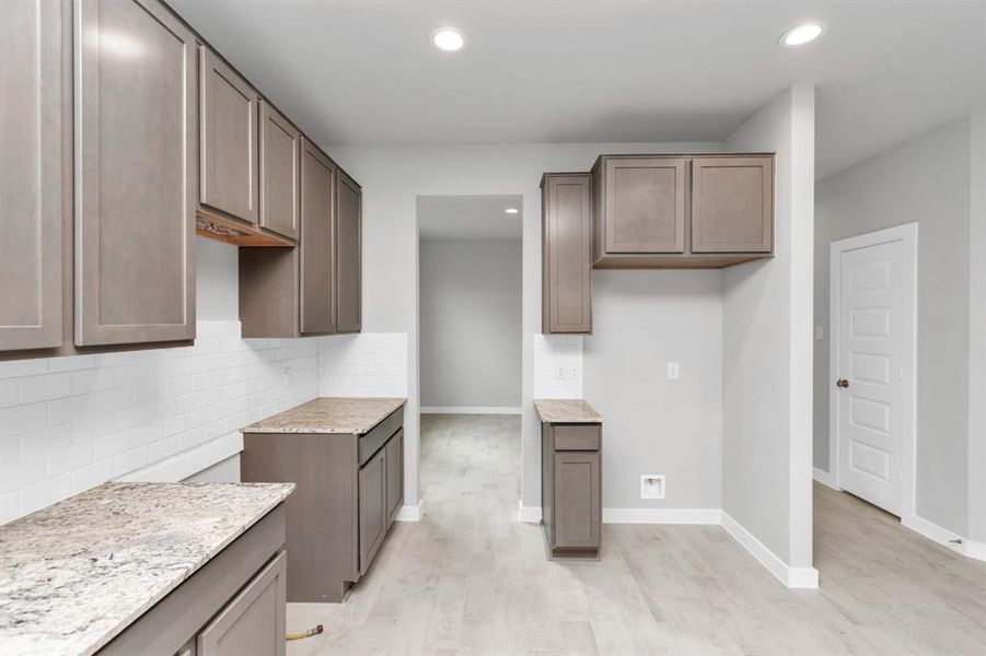 Culinary haven, featuring granite countertops, a tile backsplash, stainless steel appliances (to be installed), and 42” upper cabinets. Sample photo of completed home with similar floor plan. As-built interior colors and selections may vary.