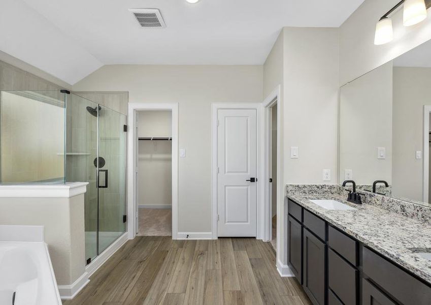 Master bathroom with a dual sink vanity, step in shower, and a soaking tub