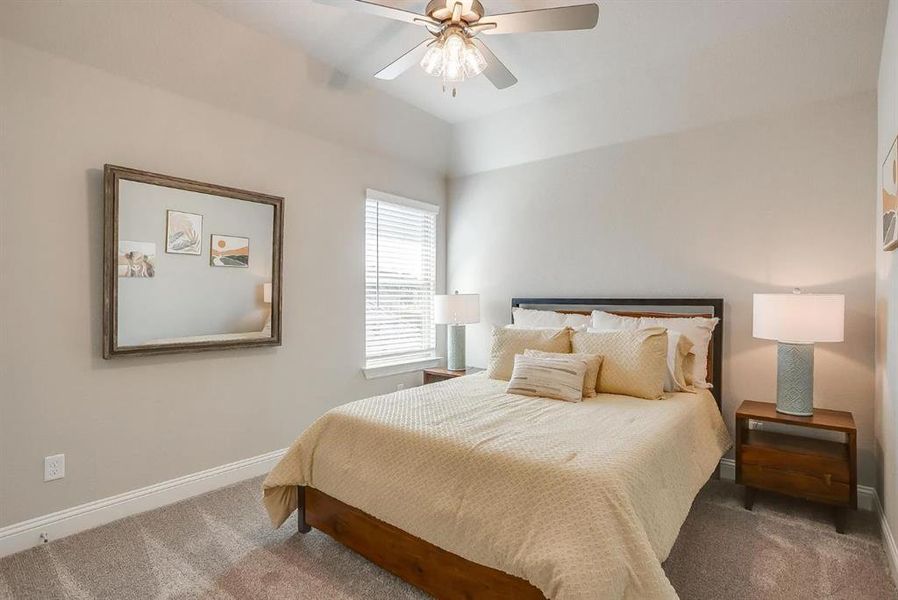 Bedroom with lofted ceiling, ceiling fan, and carpet