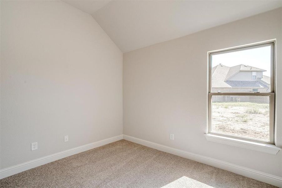 Carpeted empty room featuring lofted ceiling