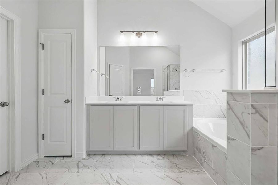 Bathroom with double vanity, light marble finish flooring, a bath, a marble finish shower, and lofted ceiling