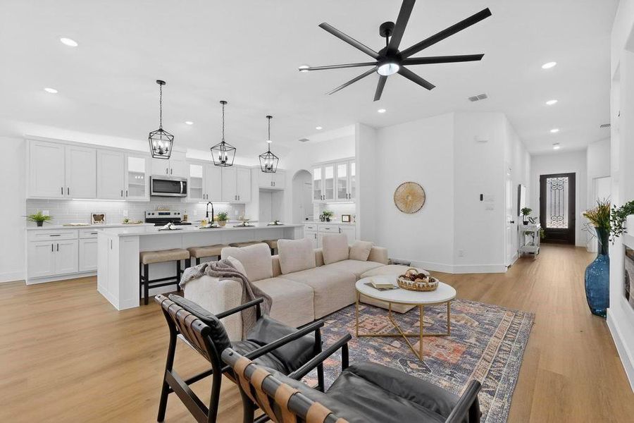 Living area featuring arched walkways, a ceiling fan, light wood-type flooring, and recessed lighting Living area featuring arched walkways, a ceiling fan, light wood-type flooring, and recessed lighting