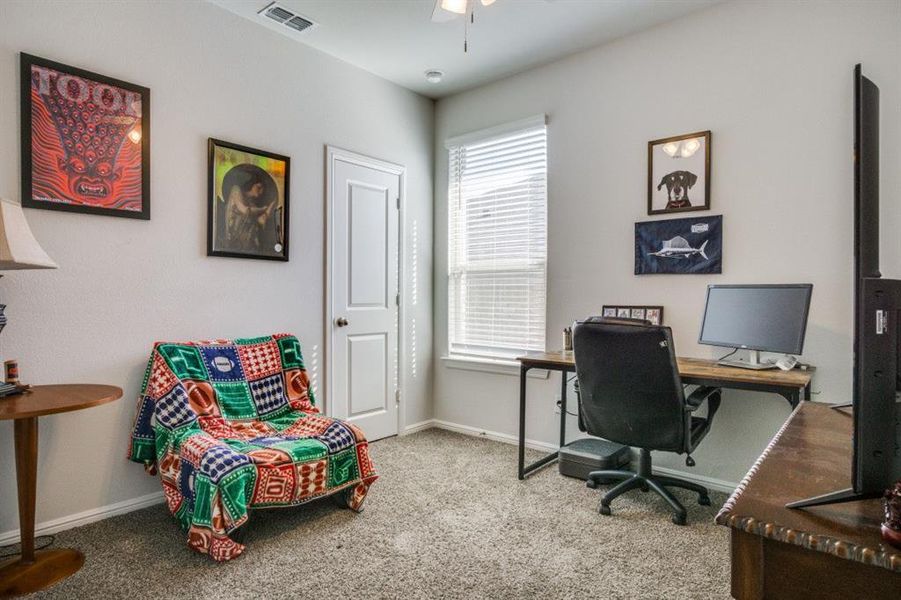 Home office with a ceiling fan, carpet, visible vents, and baseboards