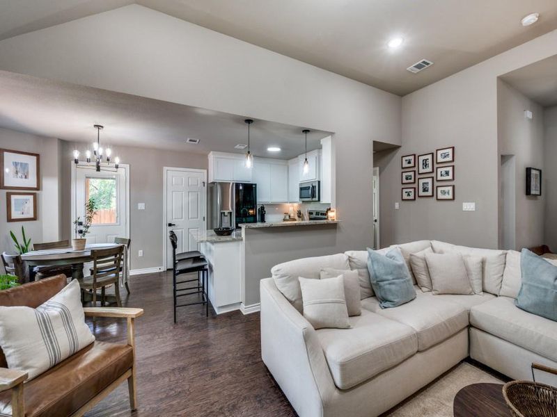 Living room with dark wood-style flooring, a chandelier, recessed lighting, baseboards, and vaulted ceiling Living room with dark wood-style flooring, a chandelier, recessed lighting, baseboards, and vaulted ceiling