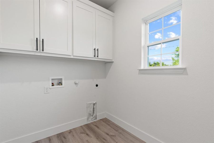 Laundry area featuring hookup for a gas dryer, cabinets, light wood-type flooring, hookup for a washing machine, and electric dryer hookup