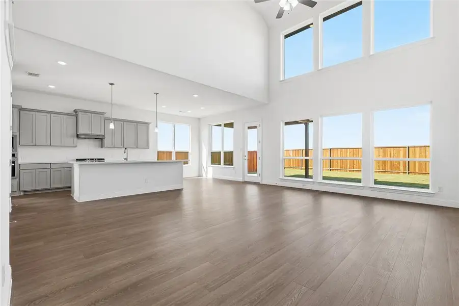 Unfurnished living room with dark wood finished floors, a ceiling fan, recessed lighting, and a high ceiling Unfurnished living room with dark wood finished floors, a ceiling fan, recessed lighting, and a high ceiling