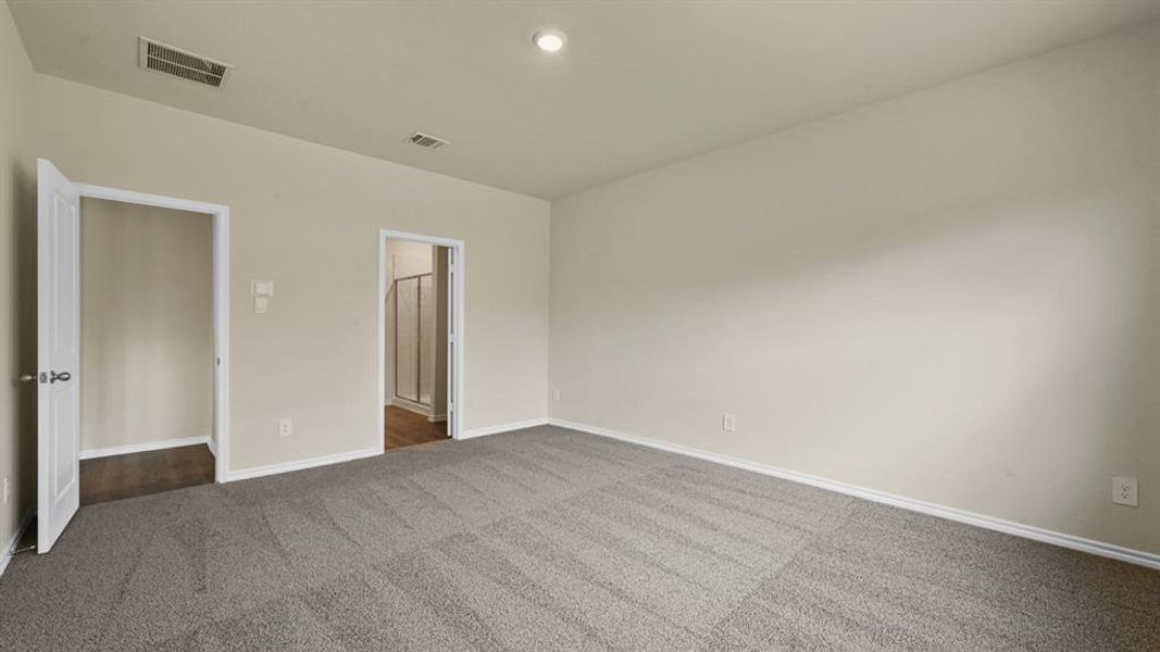 Spacious room featuring neutral wall tones, gray patterned carpet, and white baseboards