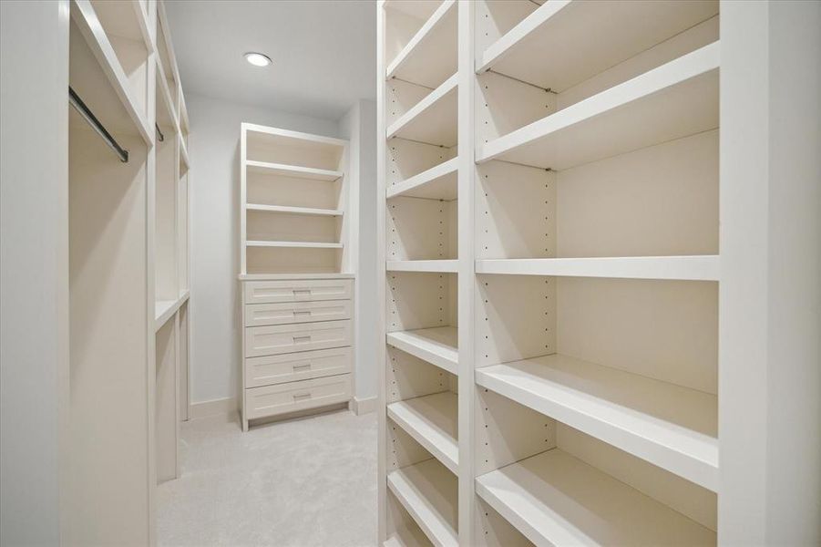 Custom shelving and built-in drawers create a highly organized and functional space in the primary closet. Open shelves provide ample room for shoes, accessories, and folded items, while hanging rods accommodate a variety of wardrobe needs. Clean lines and a neutral palette maintain a sleek and modern aesthetic, blending style with practicality. Thoughtful layout ensures easy access and maximum storage efficiency.