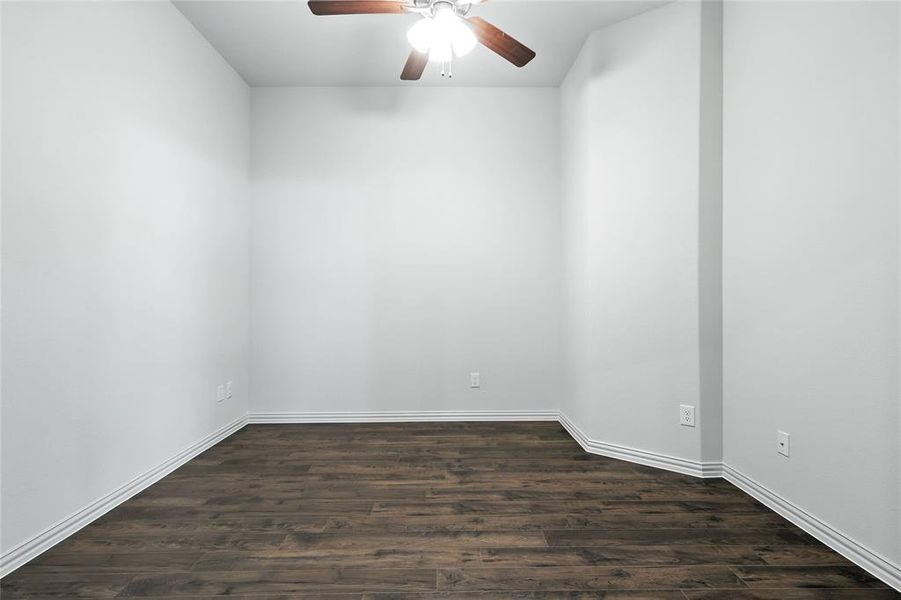 Empty room with dark wood-type flooring and a ceiling fan Empty room with dark wood-type flooring and a ceiling fan