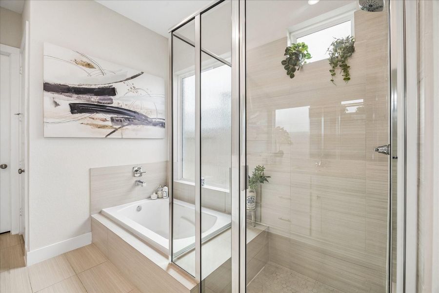 Unwind in the glass shower with built-in bench or enjoy a soak in the tub, beautifully positioned beneath a large privacy window that fills the space with natural light.