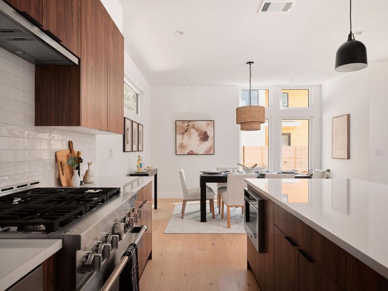 Kitchen with dark brown cabinetry, modern cabinets, extractor fan, and stainless steel appliances Kitchen with dark brown cabinetry, modern cabinets, extractor fan, and stainless steel appliances