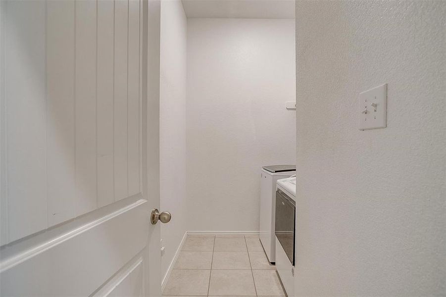 Clothes washing area with separate washer and dryer and light tile patterned floors