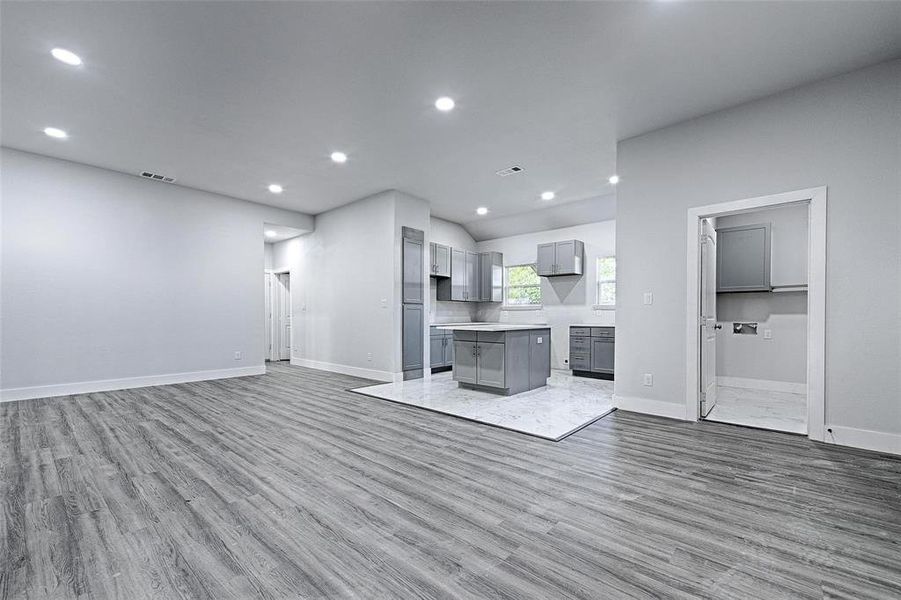 Kitchen with gray cabinetry, light hardwood / wood-style flooring, lofted ceiling, and a kitchen island