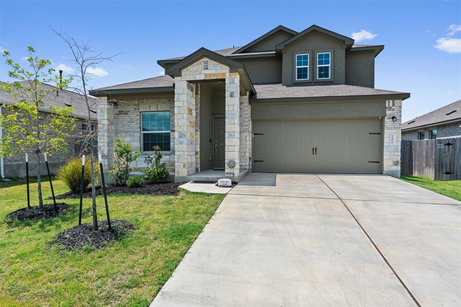 View of front facade featuring stone siding, stucco siding, concrete driveway, an attached garage, and a shingled roof