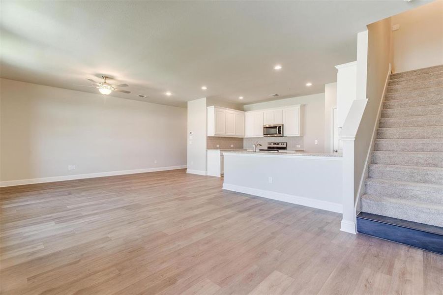 Unfurnished living room with ceiling fan and light hardwood / wood-style flooring