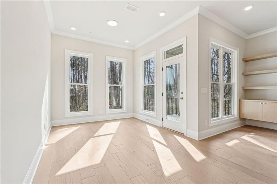 Sunroom flex space, open to back deck off Main level- use this space for a home office, breakfast or reading space- it has the best views in the entire community .  Just outside these doors is natural wooded space with a gravel path seating.  Hang out an