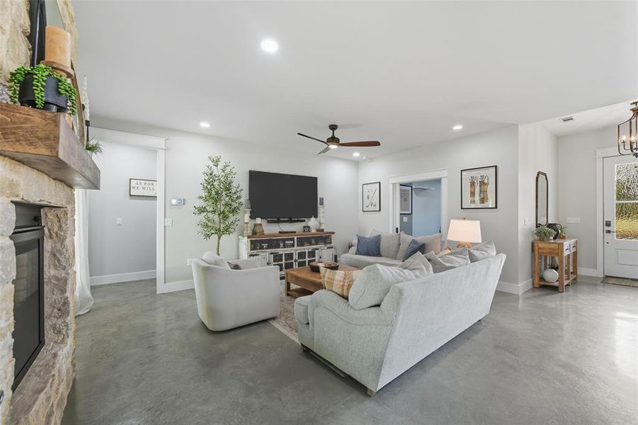 Living room with finished concrete floors, recessed lighting, a fireplace, and a ceiling fan Living room with finished concrete floors, recessed lighting, a fireplace, and a ceiling fan