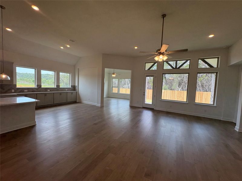 Unfurnished living room with ceiling fan, healthy amount of natural light, dark wood-style flooring, baseboards, and recessed lighting Unfurnished living room with ceiling fan, healthy amount of natural light, dark wood-style flooring, baseboards, and recessed lighting