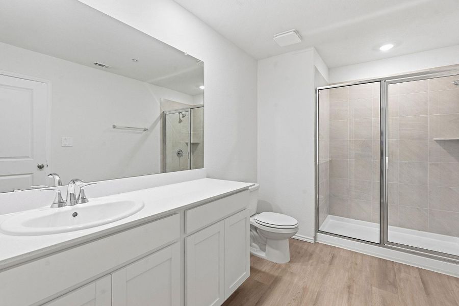 Bathroom featuring a single vanity with a white countertop, chrome faucet, and a large wall-mounted mirror