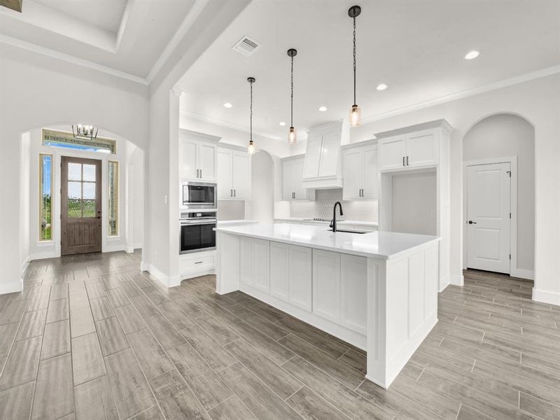 Kitchen featuring arched walkways, white cabinetry, wood finish floors, crown molding, and stainless steel appliances