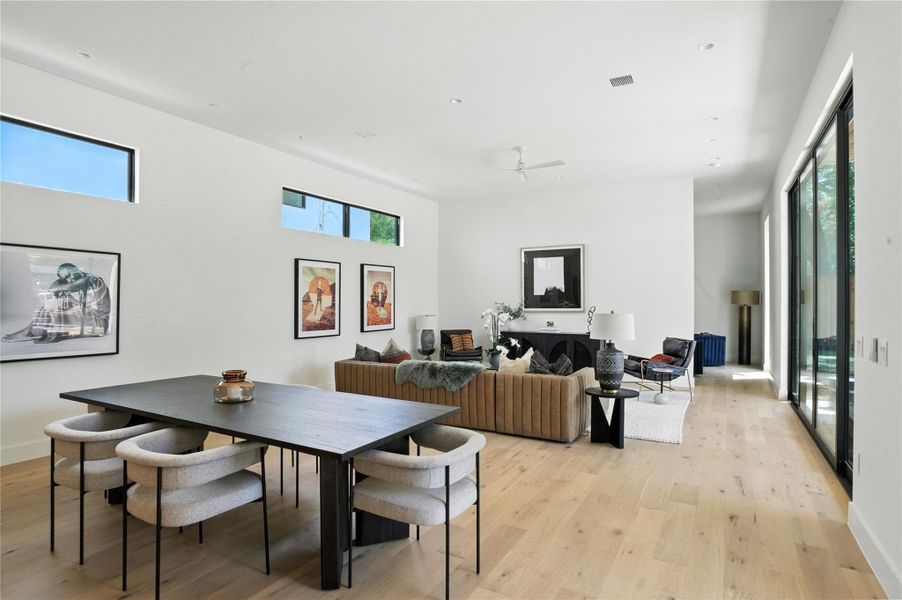 Dining area featuring light wood-style floors, plenty of natural light, and a towering ceiling Dining area featuring light wood-style floors, plenty of natural light, and a towering ceiling