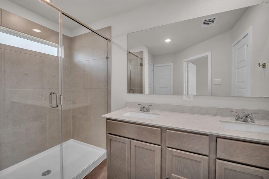 Full bath with a shower stall, double vanity, and recessed lighting Full bath with a shower stall, double vanity, and recessed lighting