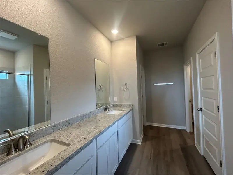 Bathroom featuring double vanity, wood finished floors, a tile shower, and recessed lighting Bathroom featuring double vanity, wood finished floors, a tile shower, and recessed lighting
