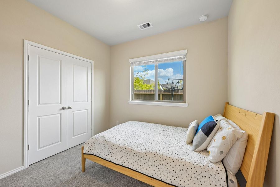 Cozy bedroom with soft carpet, featuring a large window for natural light and a spacious closet for storage.