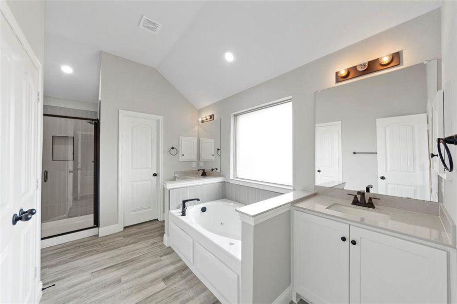 Bathroom featuring separate shower and tub, hardwood / wood-style floors, vanity, and vaulted ceiling