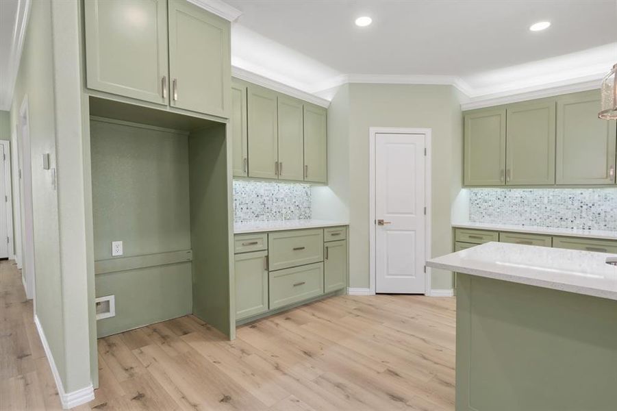 Kitchen featuring light wood-type flooring, tasteful backsplash, and green cabinetry