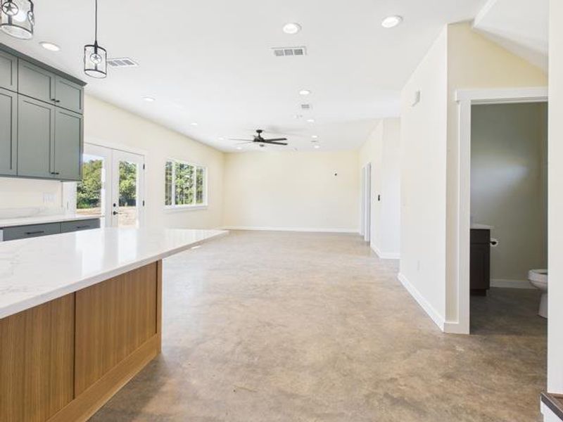 Kitchen with concrete flooring, decorative light fixtures, french doors, open floor plan, and recessed lighting