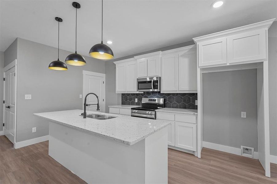 Kitchen featuring sink, appliances with stainless steel finishes, a center island with sink, white cabinets, and light hardwood / wood-style floors