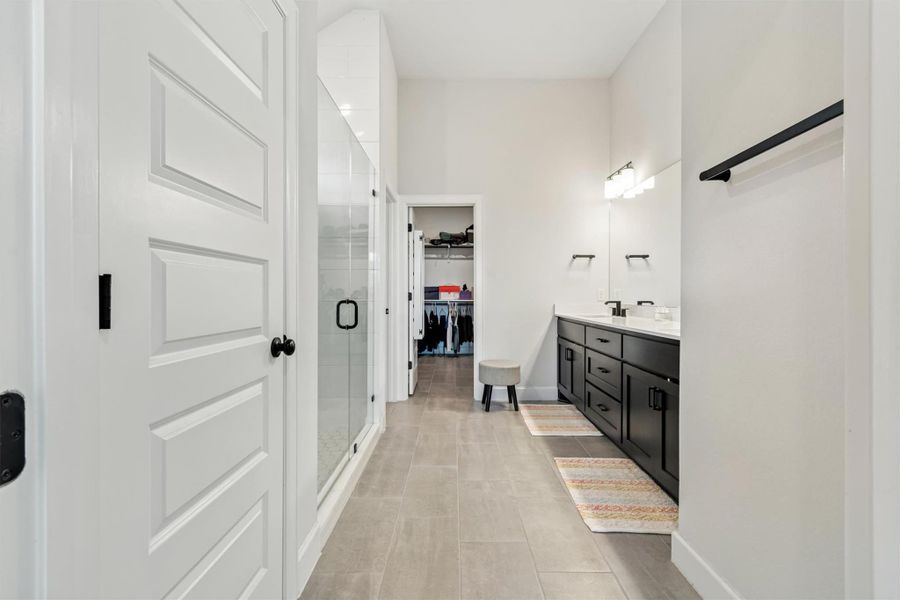 Bathroom featuring double vanity, a shower stall, a spacious closet, and light tile patterned flooring Bathroom featuring double vanity, a shower stall, a spacious closet, and light tile patterned flooring