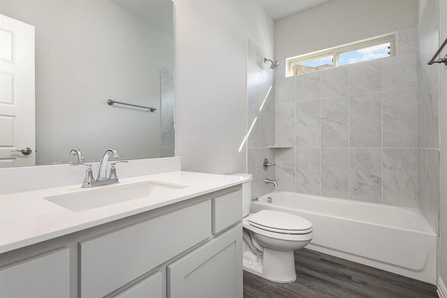 Full bathroom featuring vanity, toilet, tiled shower / bath, and hardwood / wood-style flooring