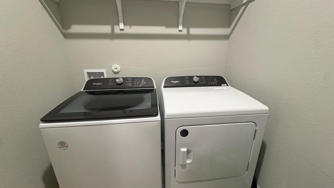 Functional laundry space featuring modern appliances and convenient overhead shelving.